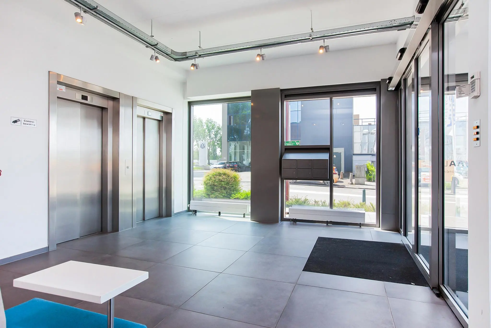 Moderne entreehal met twee liften, grote ramen en postvakken aan de Laan der Verenigde Naties.